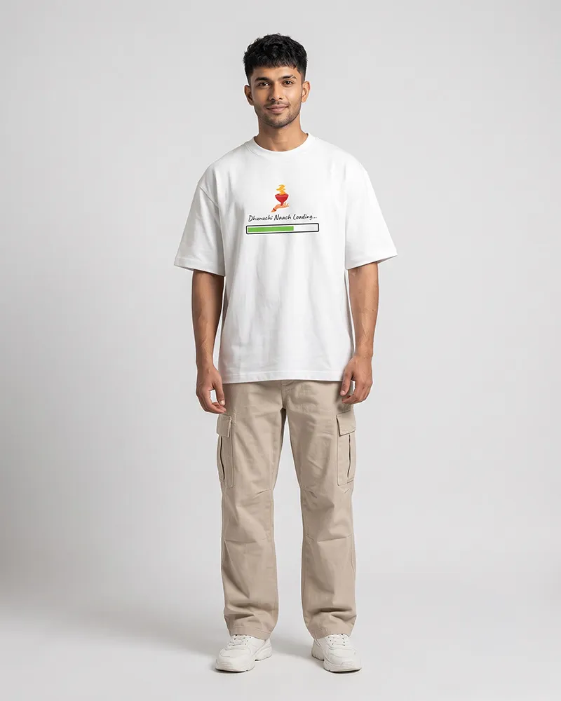 Man standing in a white oversized T-shirt with a loading bar graphic, beige cargo pants, and white sneakers against a gray studio background.
