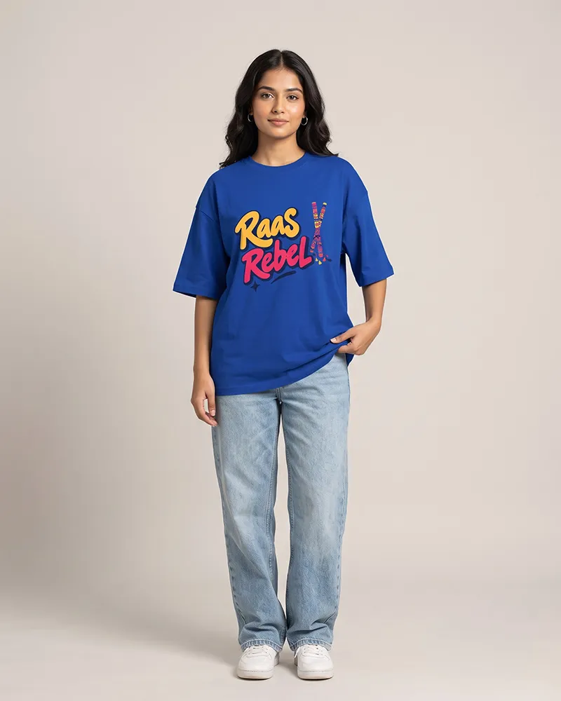 Model wearing a blue oversized T-shirt with a colorful 'Raas Rebel' graphic, paired with light-wash jeans and white sneakers.